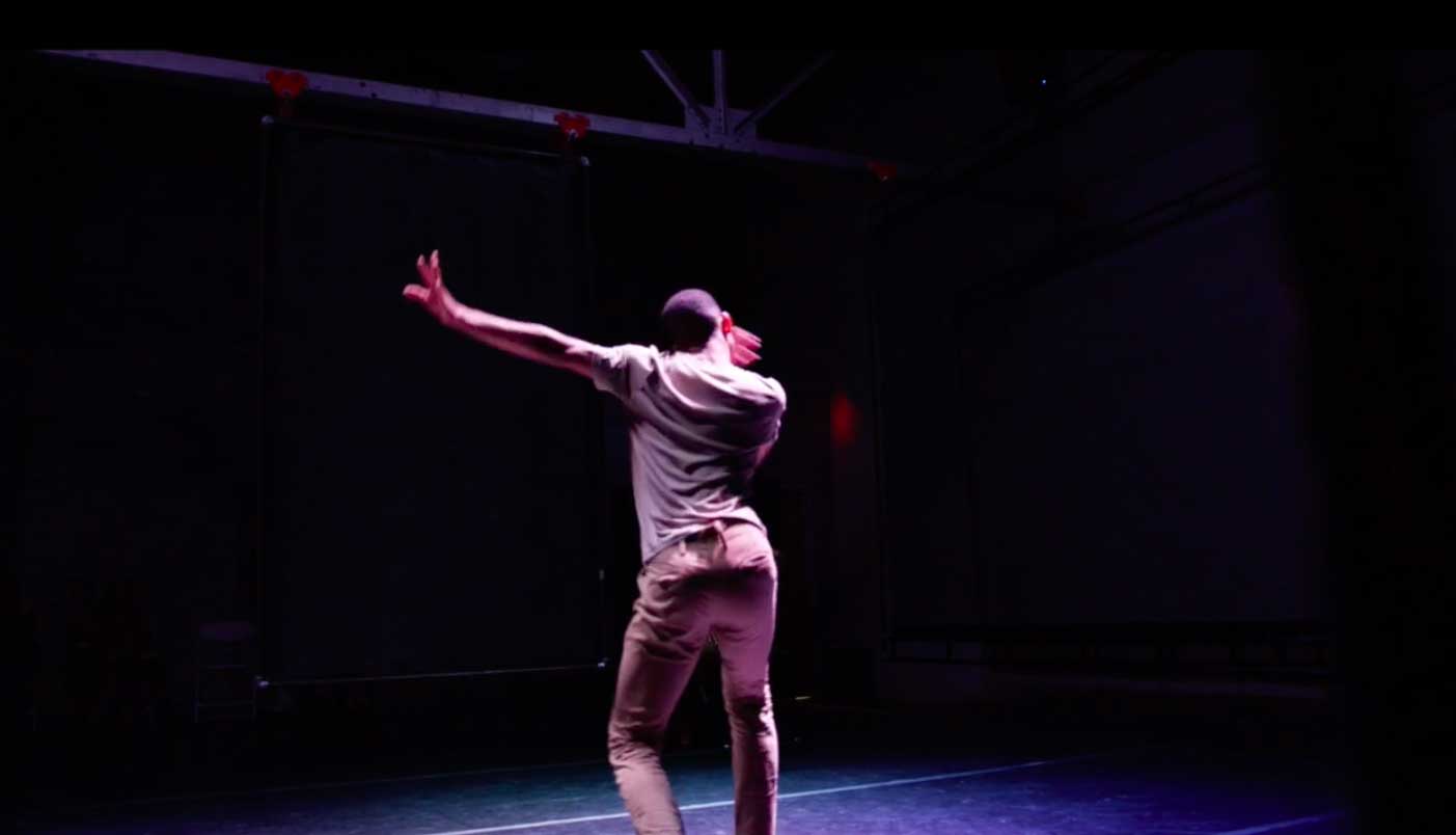 Man dancing on a stage with his back to the viewer