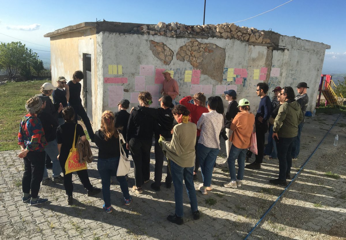 People standing around small building in landscape