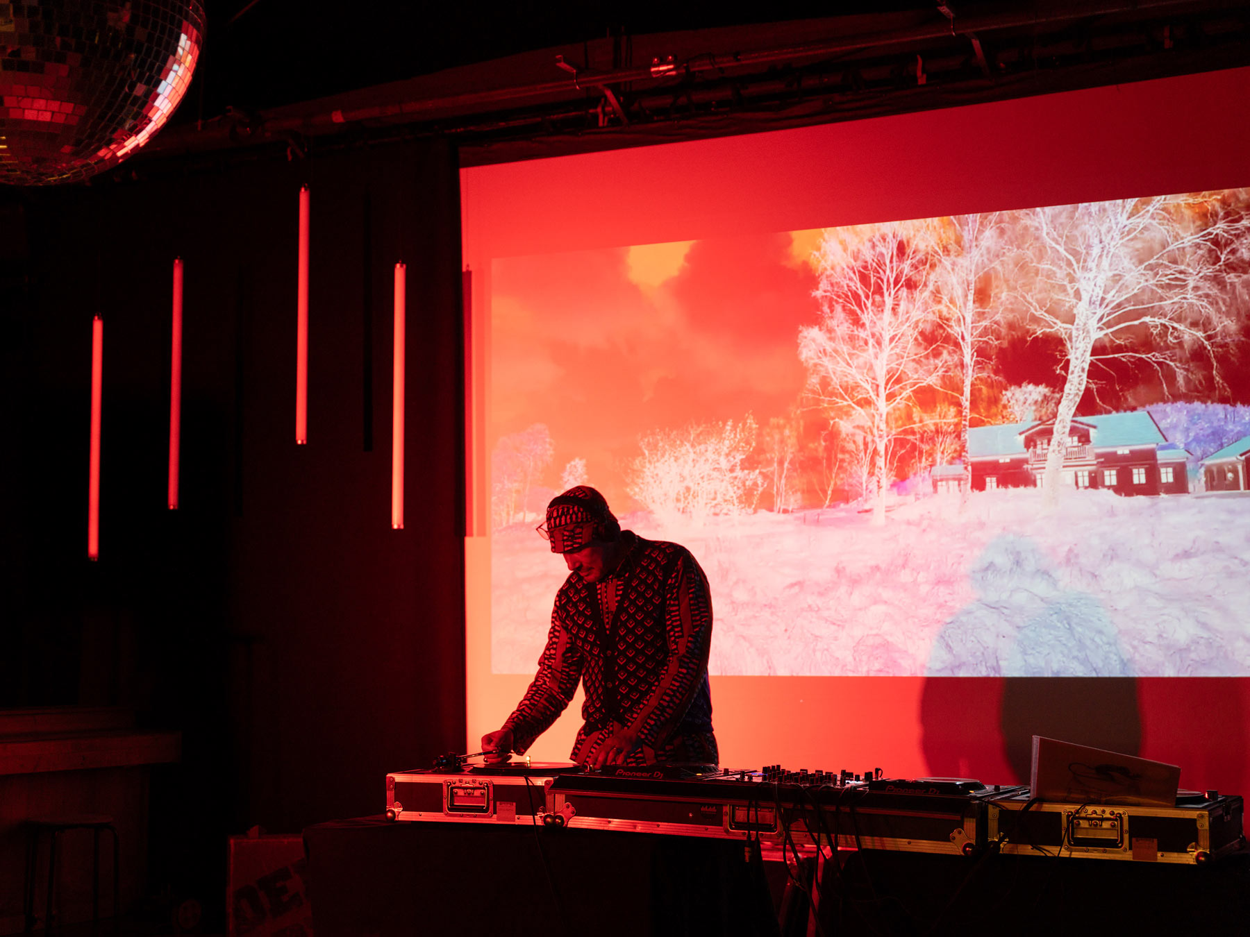 DJ in front of his decks and an image of a house in the snow