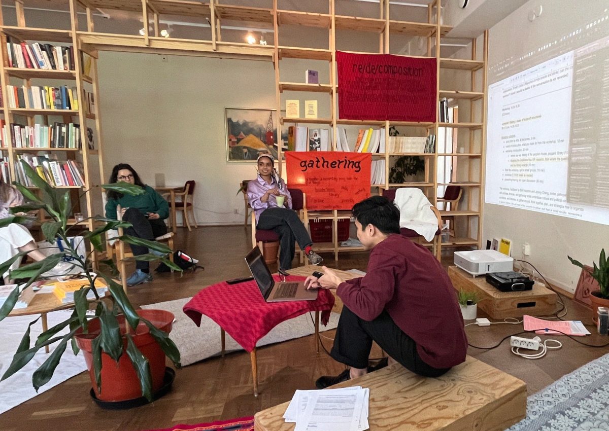 People sitting in a small library talking and on person showing slides from a computer