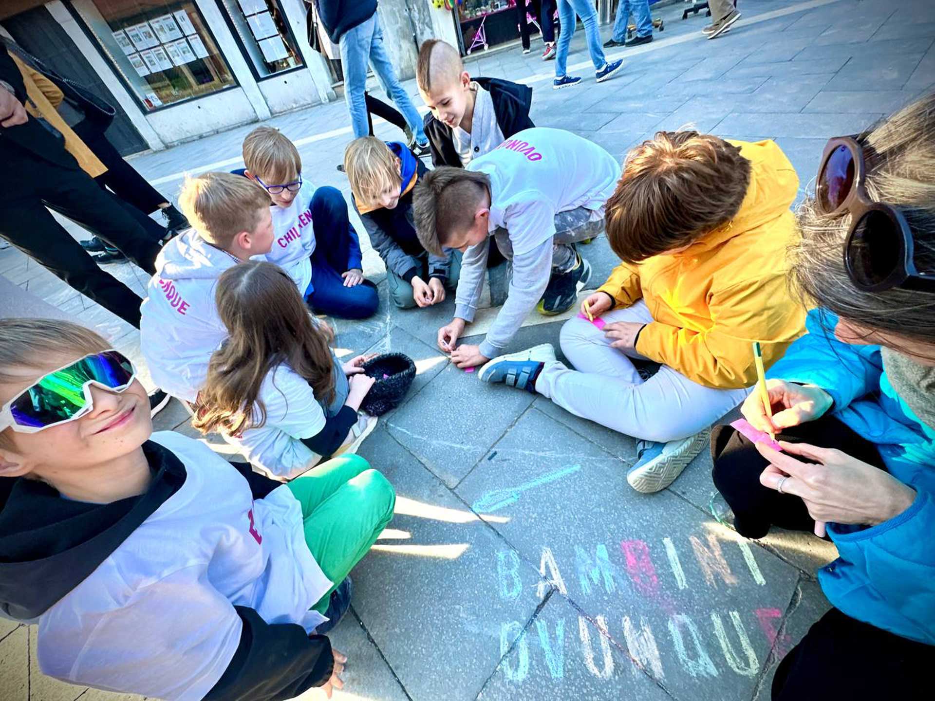Children sitting in the street drawing with crayons