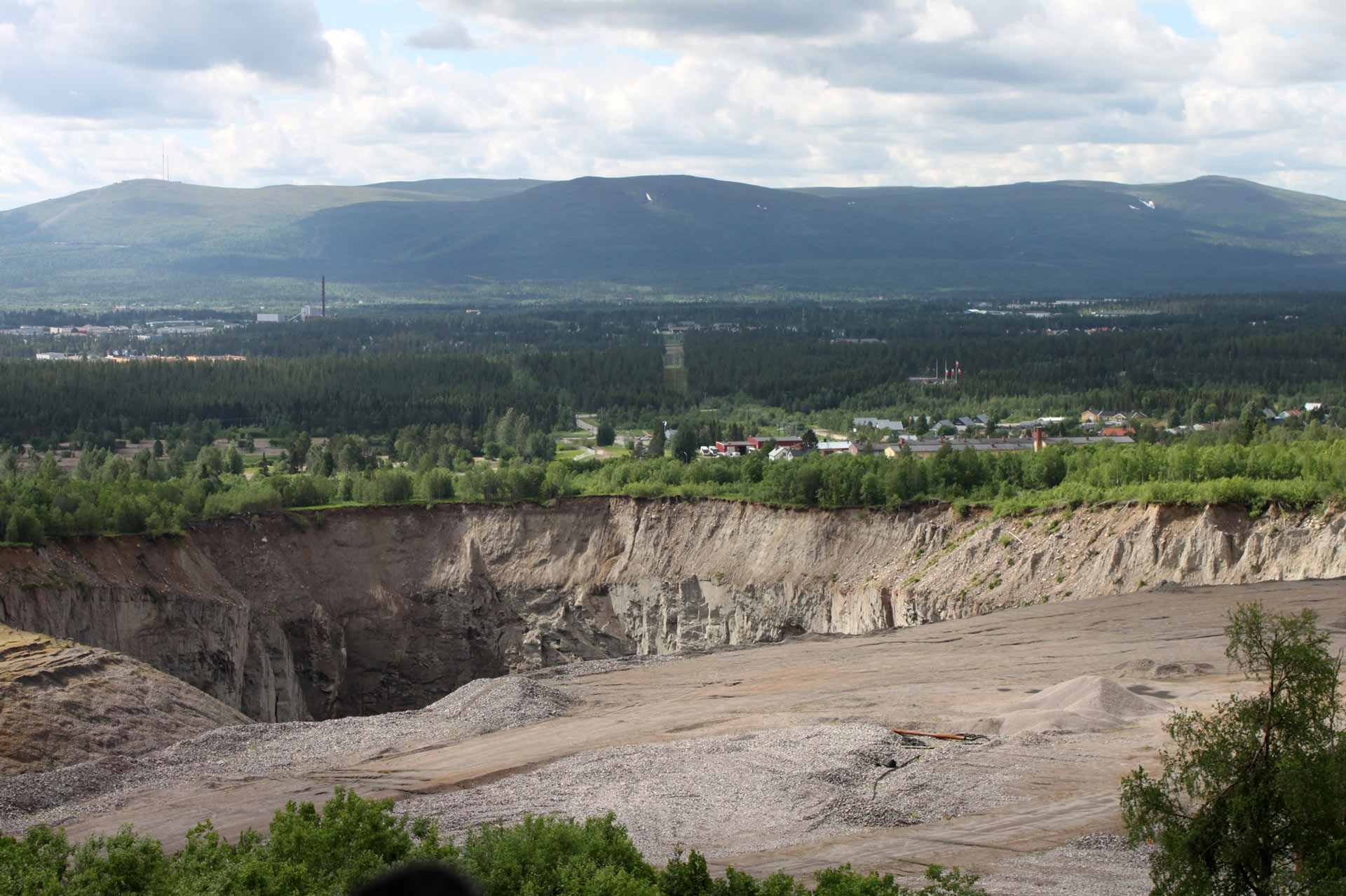 Lanscape with an open mine in the foreground , forrest and mountains in the background