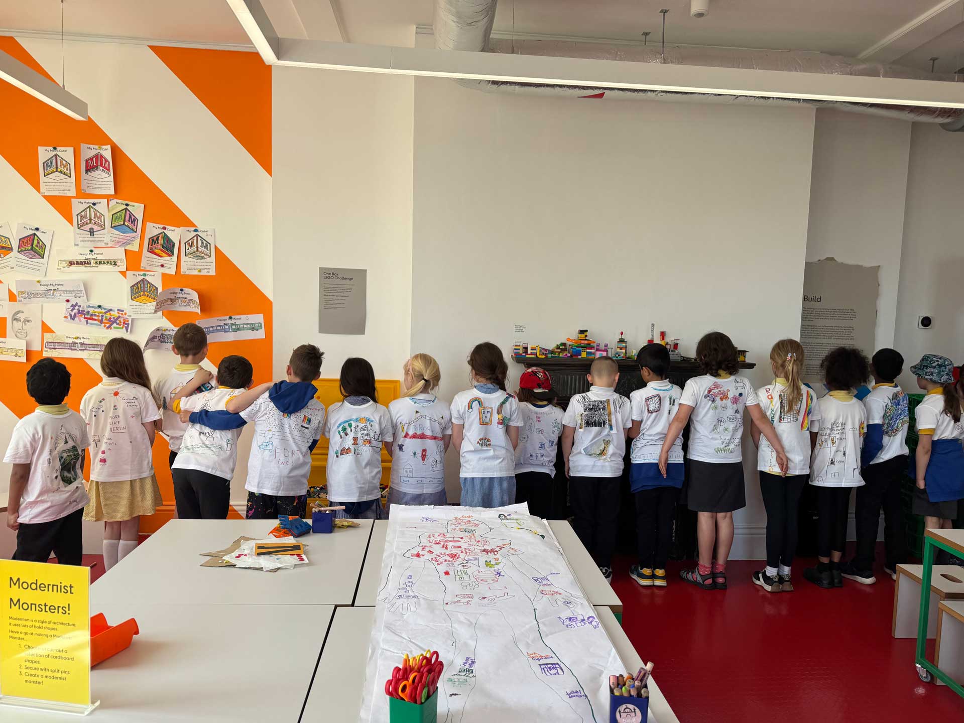 Children lined up with their backs with illustrated t-shirts to a spectator